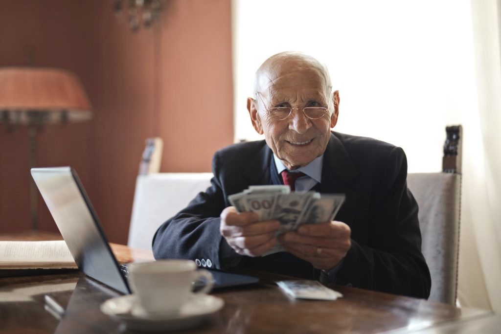 Photo by Andrea Piacquadio: https://www.pexels.com/photo/confident-senior-businessman-holding-money-in-hands-while-sitting-at-table-near-laptop-3823493/