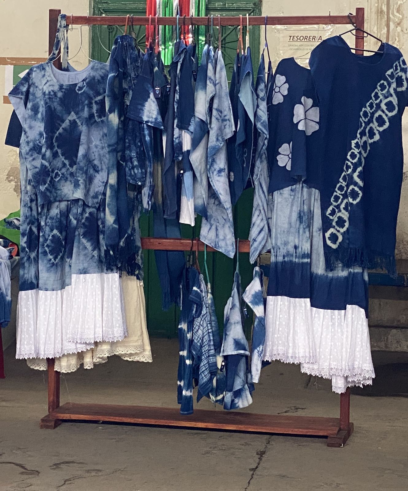 Vestidos y textiles con diseños azules y blancos colgados en un puesto de la Feria Cultural del Añil en Santiago Niltepec